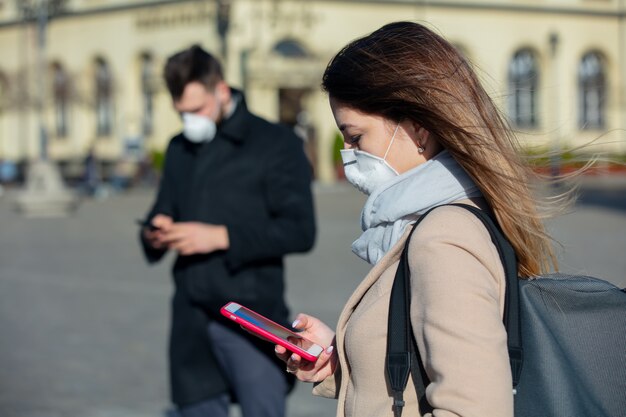 Vrouw en jongen in maskers met behulp van mobiele telefoon