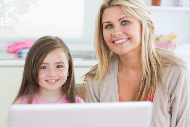 Vrouw en kind zitten en lachend met laptop