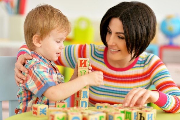 Vrouw en kleine jongen spelen met kubussen thuis