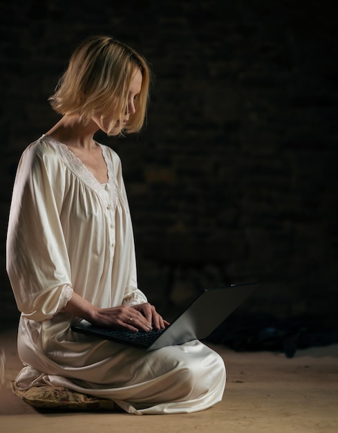 Vrouw en laptop in een lege donkere kamer Deadline veel werk privacy Vrouw van middelbare leeftijd in een wit overhemd