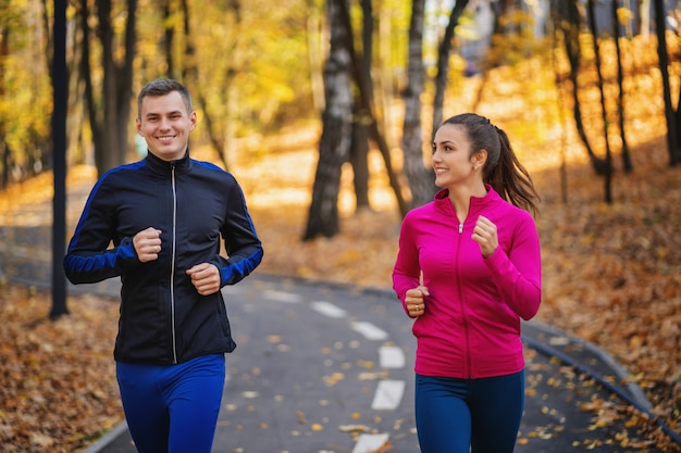 Vrouw en man die of in park tijdens de herfst op een heuvel aanstoten lopen