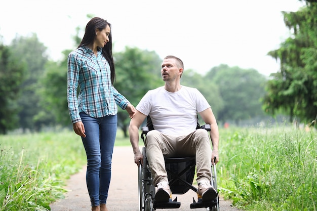 Vrouw en man in een rolstoel lopen in park en praten