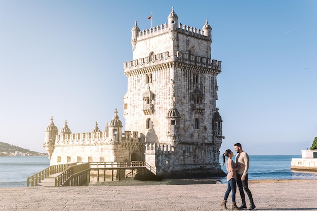 Vrouw en man kijken elkaar aan met de belemtoren en de rivier de Taag op de achtergrond in Lissabon Portugal