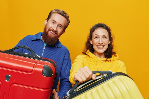 Vrouw en man lachende koffers in de hand met gele en rode koffer glimlachend vrolijk en scheve gele achtergrond gaan op reis familie vakantie reis jonggehuwden