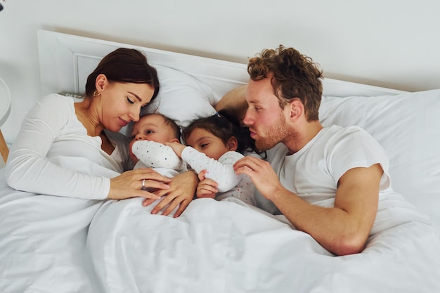 Vrouw en man liggen op bed met hun kinderen interieur en ontwerp van mooie moderne slaapkamer overdag