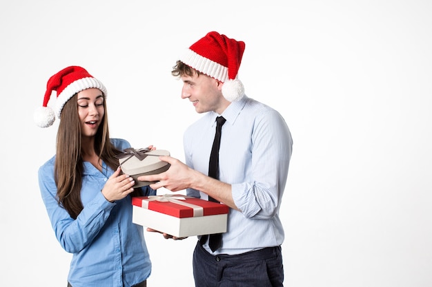 Vrouw en man met cadeau voor Nieuwjaar en Kerstmis in kerstmuts geïsoleerd