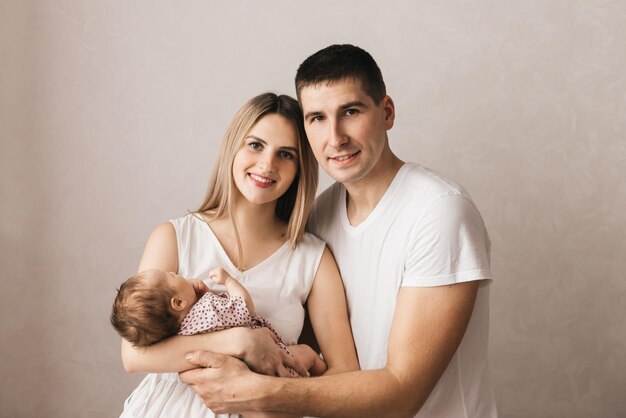 Vrouw en man met een pasgeboren moeder, vader en baby Close-up portret van jonge lachende familie met pasgeboren op de handen Gelukkige familie op een background