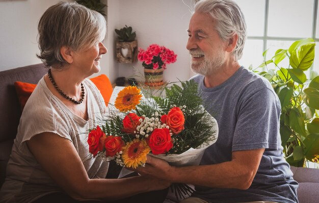 Vrouw en man vieren thuis een romantische Valentijnsdag met een groot boeket bloemen. Twee senioren verliefd