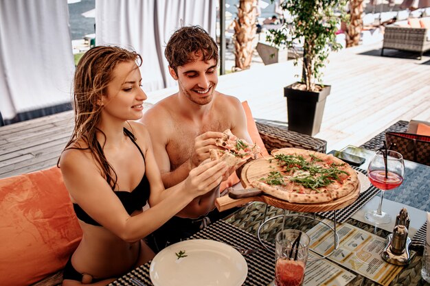 Vrouw en man zitten in geopende restaurant en lekkere heerlijke pizza eten