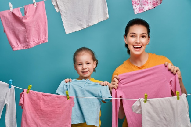 Vrouw en meisje hangen kleren aan een touw