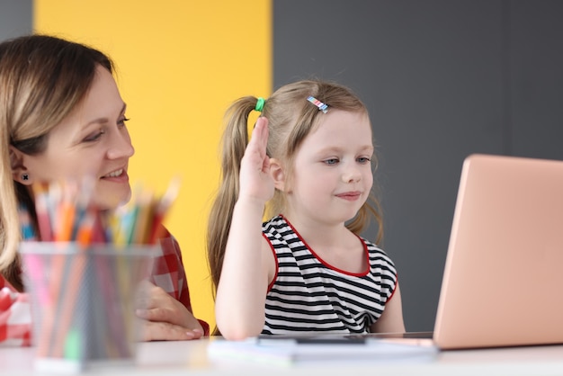 Vrouw en moeder zitten aan tafel en communiceren via laptopscherm