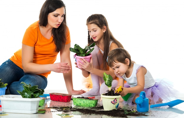 Vrouw en twee meisjes planten bloemen in bloempotten