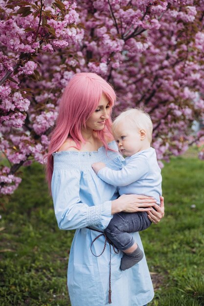 Vrouw en zoontje in de natuur spelen in het lentepark in de bloeiende Sakura-tuinen Kleine jongen en moeder hebben een leuke tijd tijdens weekendactiviteiten