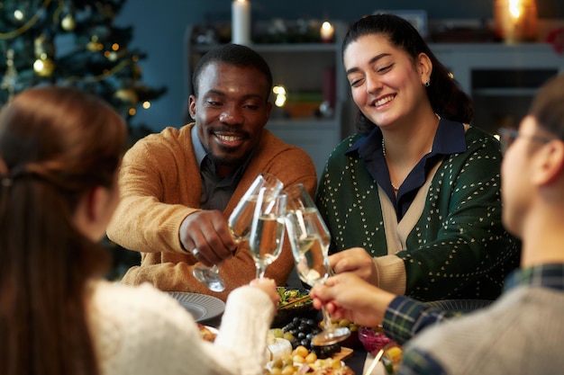 Vrouw en zwarte man klinken glazen vieren feest met vrienden op kerstavond