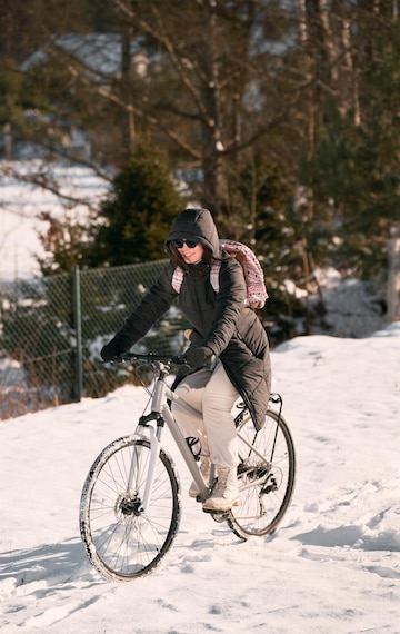 Kano samenwerken Vaarwel Vrouw fietst in de winter het gelukkige meisje draagt een zwarte winterjas  en een zonnebril tijdens het fietsen | Premium Foto