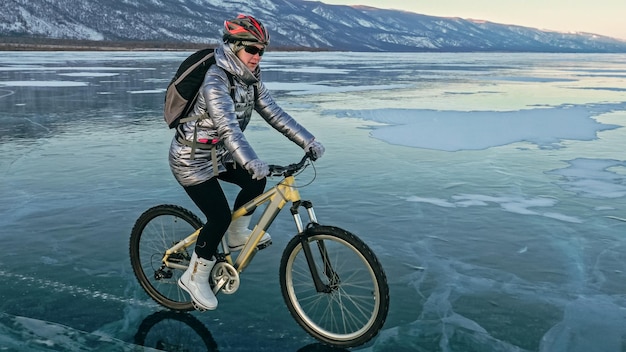 Foto vrouw fietst op het ijs banden op de fiets zijn afgedekt met