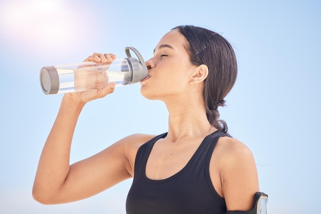 Vrouw fitness en drinkwater voor natuurlijke voeding of duurzaamheid na training hardlopen of buiten sporten Dorstige vrouwelijke persoon met fles mineraal voor een gezonde wellnesspauze of rust