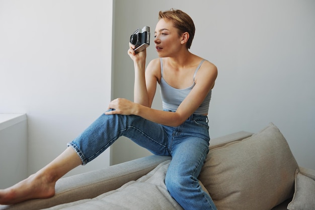 Vrouw fotograaf fotograferen in studio op oude filmcamera thuis op bank portret witte achtergrond gratis kopie ruimte freelance fotograaf