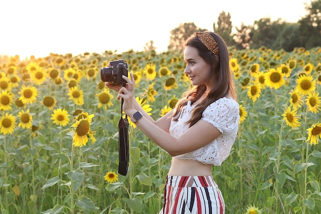 Vrouw fotograaf maakt foto's in de natuur, fotograaf maakt foto's van een prachtig veld met zonnebloemen bij zonsondergang. Hoge kwaliteit foto