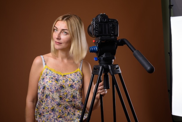 Vrouw fotograaf met DSLR camera op statief in studio