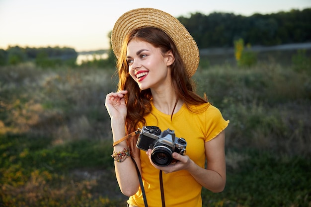 Vrouw fotograaf met hoed rode lippen natuur camera levensstijl