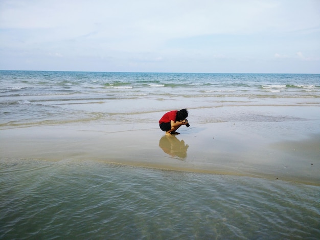 Foto vrouw fotografeert terwijl ze op een zandbank kruipt