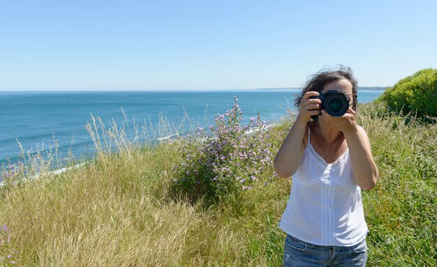 Vrouw fotograferen met camera aan de zee