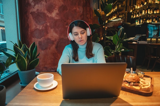 Vrouw freelancer die op laptop werkt in café die thee drinkt en hamburger kopieerruimte eet