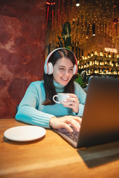 Vrouw freelancer die op laptop werkt in café die thee drinkt en hamburger kopieerruimte eet