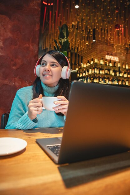 Vrouw freelancer die op laptop werkt in café die thee drinkt en hamburger kopieerruimte eet