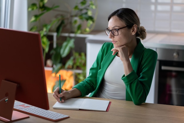 Vrouw freelancer maakt plan voor zakelijk project werken op computer in gezellig thuiskantoor met plant