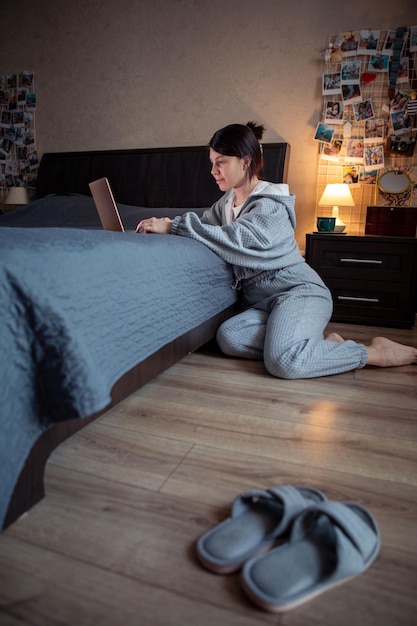 Vrouw freelancer thuis werken op laptop zittend op de vloer laptop op het bed