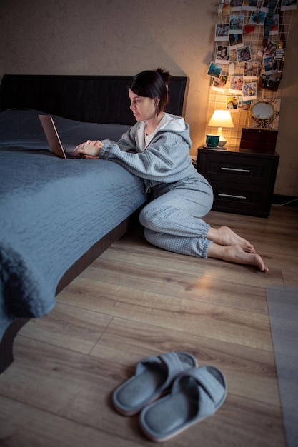 Vrouw freelancer thuis werken op laptop zittend op de vloer