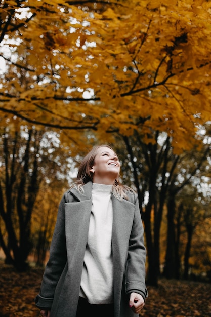 vrouw gaat langs de herfststeeg van het park een meisje in een grijze jas