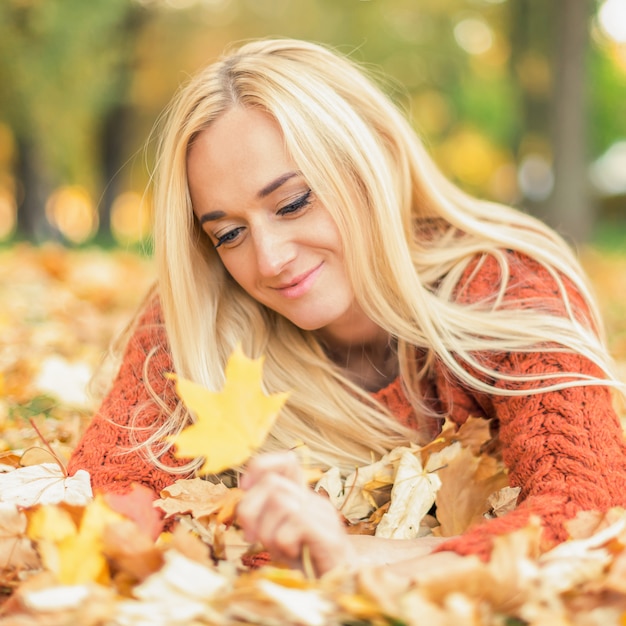 Vrouw gaat liggen op bladeren in de herfst park