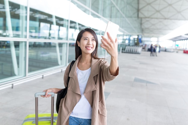 Vrouw gaat op reis en neemt selfie via de mobiele telefoon op de luchthaven