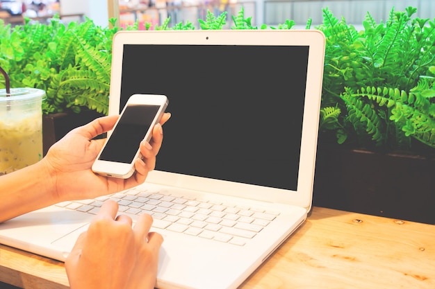 Vrouw gebruikend laptop en gebruikend smartphone.