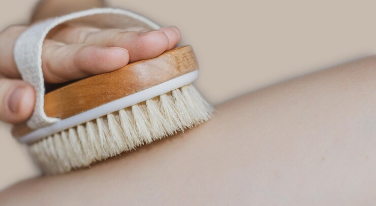 vrouw gebruikt borstel voor droge massage warme kleur beige achtergrond Droge lichaamsborstel goed om te verminderen