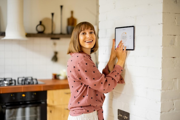 Vrouw gebruikt een digitale tablet om de temperatuur in het appartement te regelen