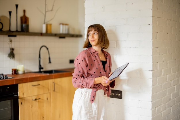 Vrouw gebruikt een digitale tablet om de temperatuur in het appartement te regelen