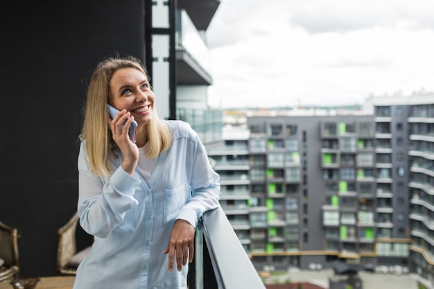 vrouw gebruikt een mobiele telefoon terwijl ze op het balkon staat