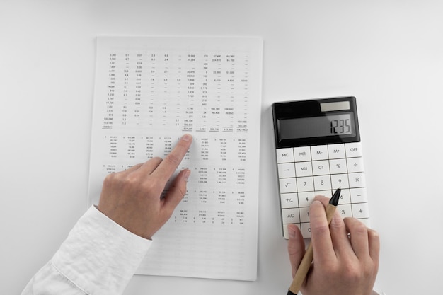 Vrouw gebruikt een rekenmachine en wijst met haar vinger naar de cijfers in de financiële documenten Financialbusiness en geldconcept