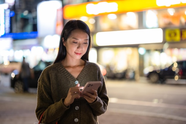 Vrouw gebruikt mobiele telefoon in de stad's nachts