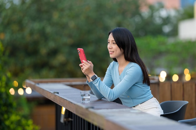 Vrouw gebruikt mobiele telefoon in een openluchtcafé