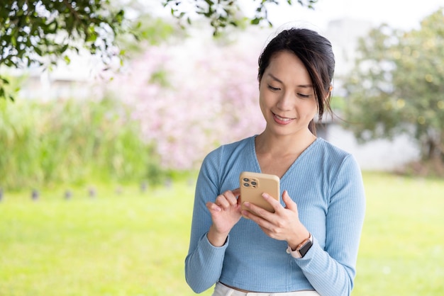 Vrouw gebruikt mobiele telefoon in het park.