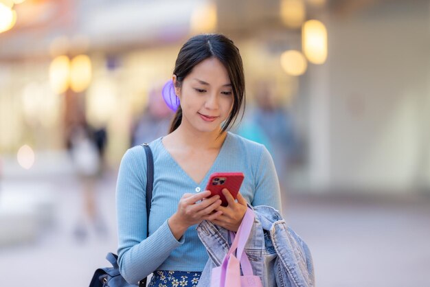 Vrouw gebruikt mobiele telefoon in het winkelgebied
