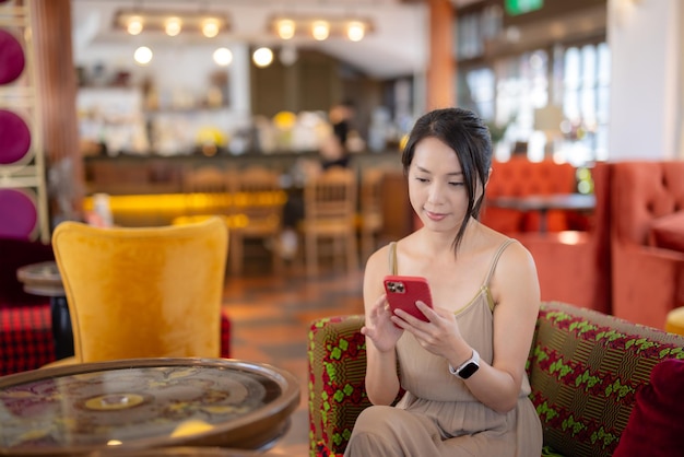 Vrouw gebruikt mobiele telefoon in koffiehuis