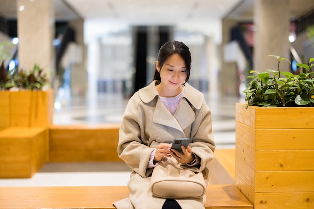 Vrouw gebruikt mobiele telefoon in winkelcentrum