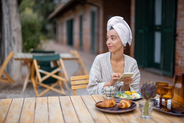 Vrouw gebruikt smartphone en ontbijt 's ochtends