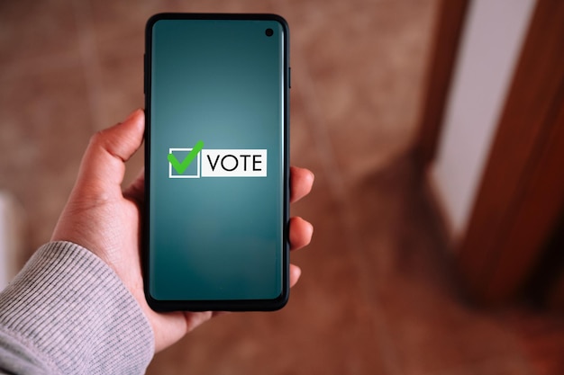 Vrouw gebruikt smartphone om online te stemmen Politiek concept Elektronisch stemmen via internet